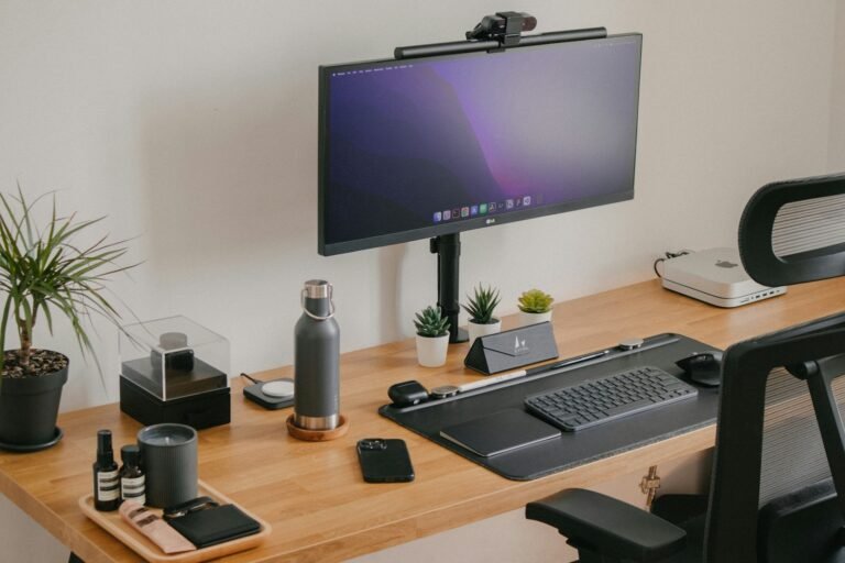 Écran sur bras articulé au-dessus d’un bureau en bois, réglé à hauteur des yeux
